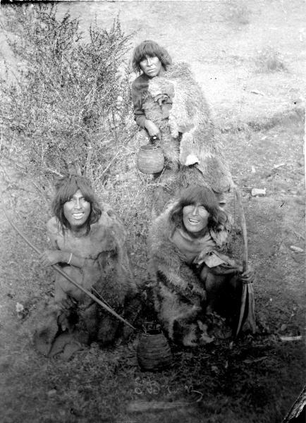 Indígenas varones con arcos y mujer con canasto